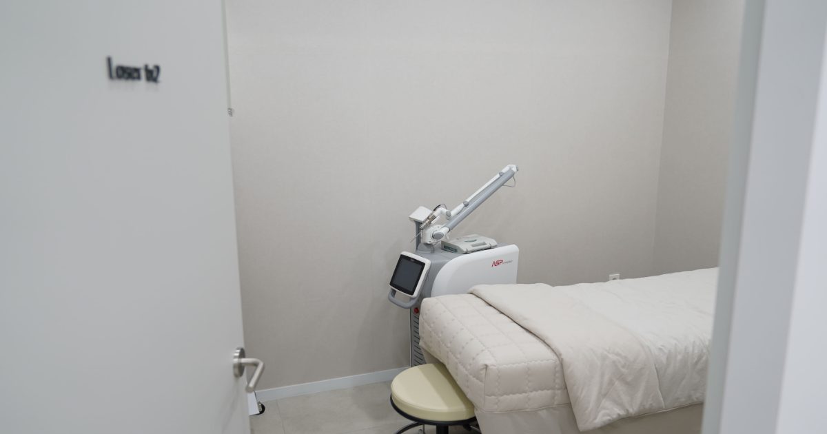 Laser treatment room with a pico laser device beside a treatment bed at the Seoul clinic